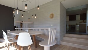 A modern dining area with a round table, white chairs, and a wooden bench.