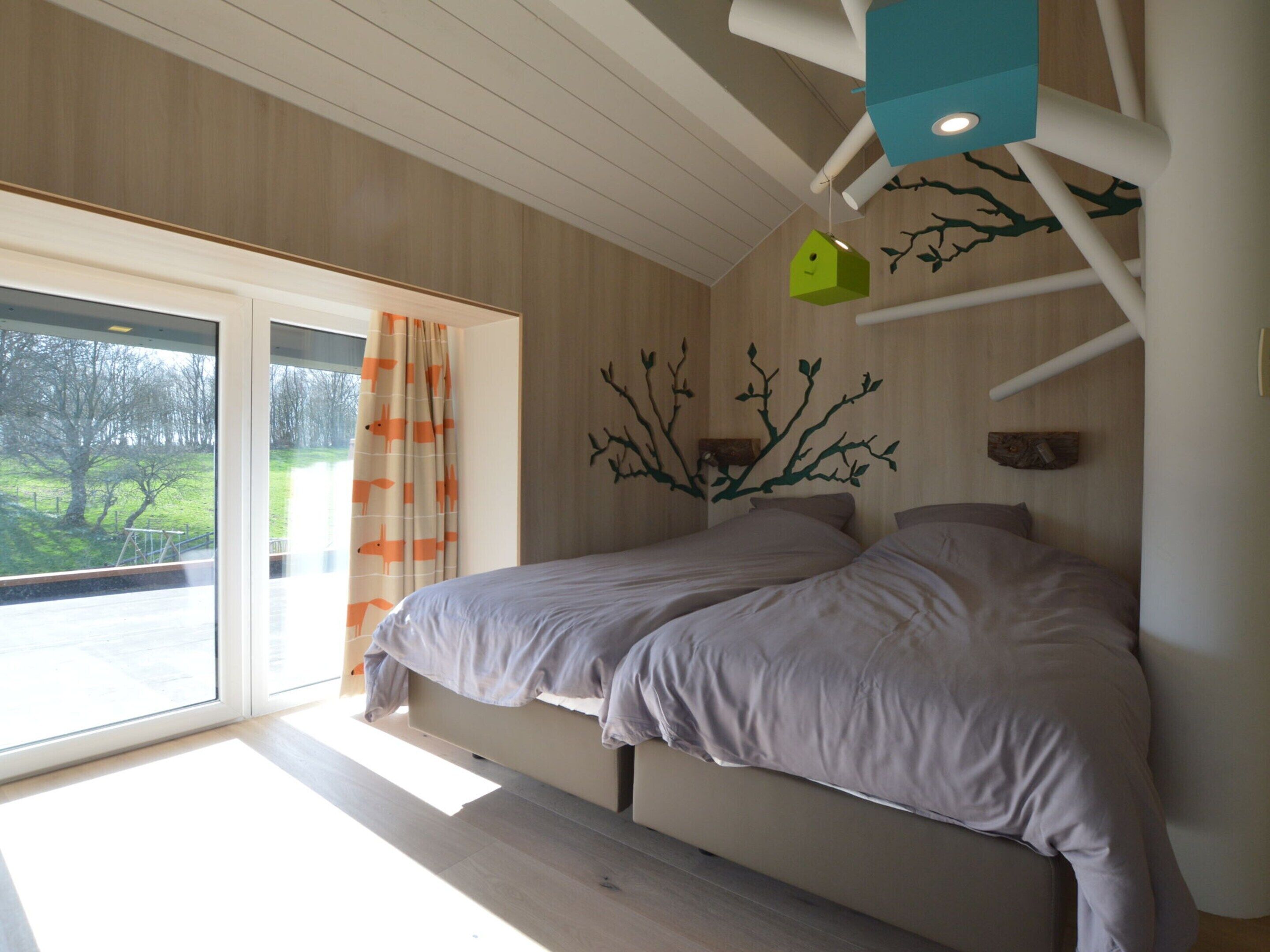 A bedroom with a bed, a window with curtains, and a wall decoration.