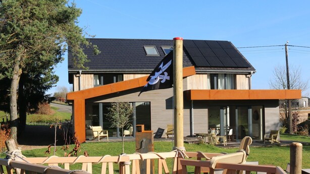 A modern house with a large deck, a flag, and a view of the surrounding landscape.