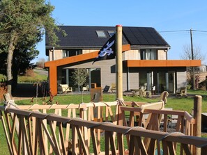 A modern house with a large deck, a flag, and a view of the surrounding landscape. - Chic Retreat Near Lake & Fens (Waimes)