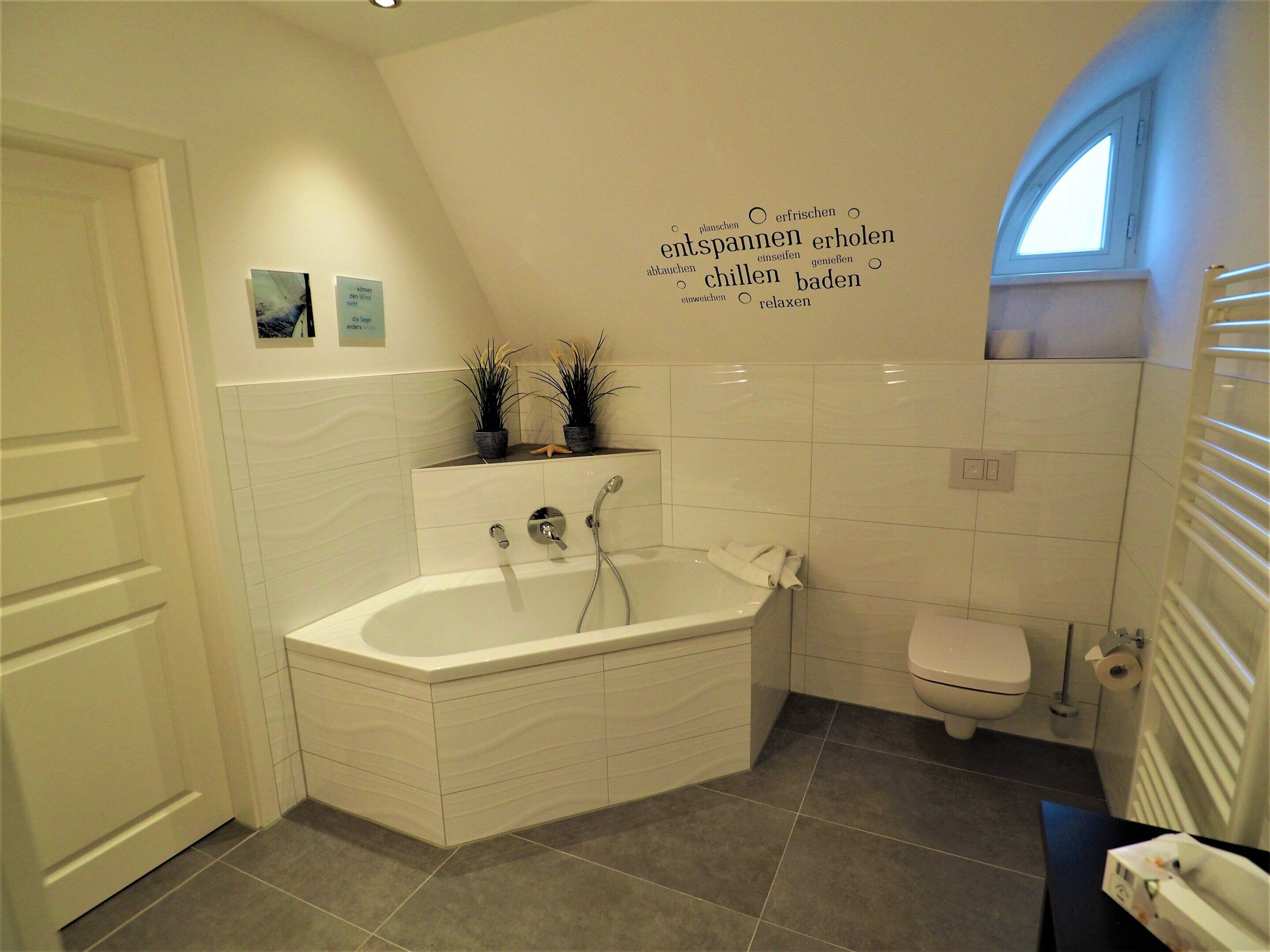 A modern bathroom with a freestanding bathtub, a toilet, and a shower area.