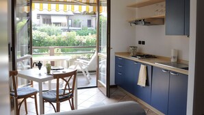 A compact kitchen with a dining area, a view of a garden, and a sliding glass door leading to an outdoor space.