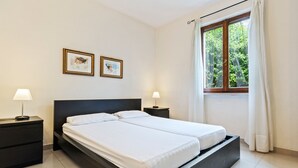 A modern bedroom with a bed, two bedside tables, and two framed pictures on the wall. - Spacious Lake Garda Villa With Private Pool, Garden and Direct Lake Access (Lazise)