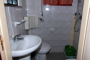 A bathroom with a sink, toilet, and mop.