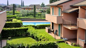 Et boligområde med swimmingpool, velplejede hække og en toetagers bygning med balkon.
