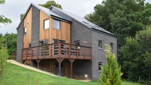 Ein modernes, zweistöckiges Haus mit einer Holzterrasse und einer Ziegelaußenwand.