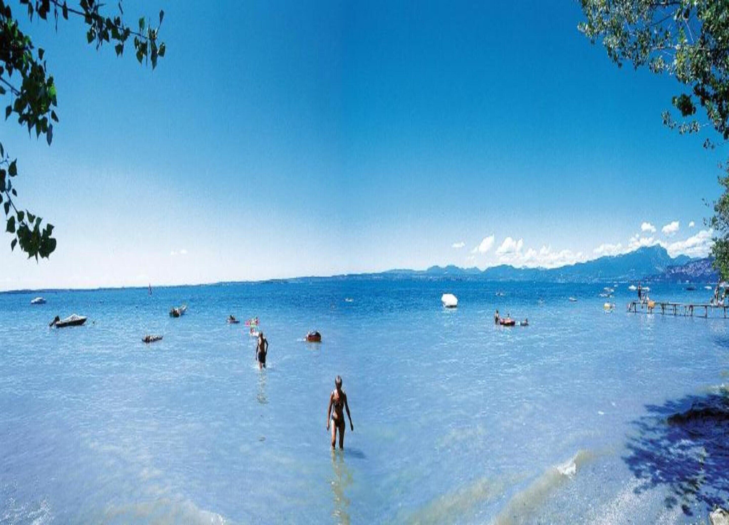 A clear blue sea with boats and people.