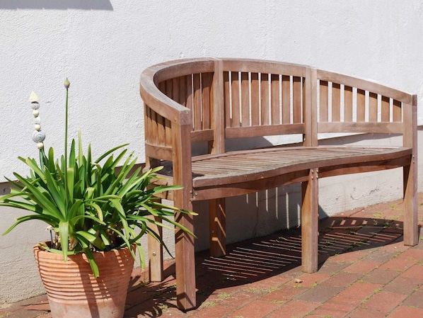 A wooden bench with a slatted backrest and a metal table in front of a white wall. - Apartment in Dargun With Pool and Terrace (Dargun)