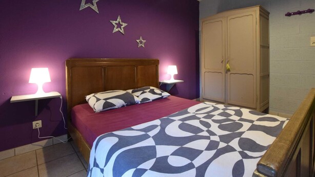 Une chambre à coucher avec un lit, deux lampes de chevet, une armoire et des décorations en forme d’étoiles sur le mur.