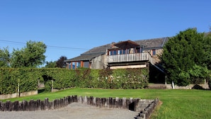 A two-story house with a balcony, surrounded by a well-maintained lawn and hedges. - Cottage in a Well-equipped and Comfortable Farmhouse (Marche-en-Famenne)
