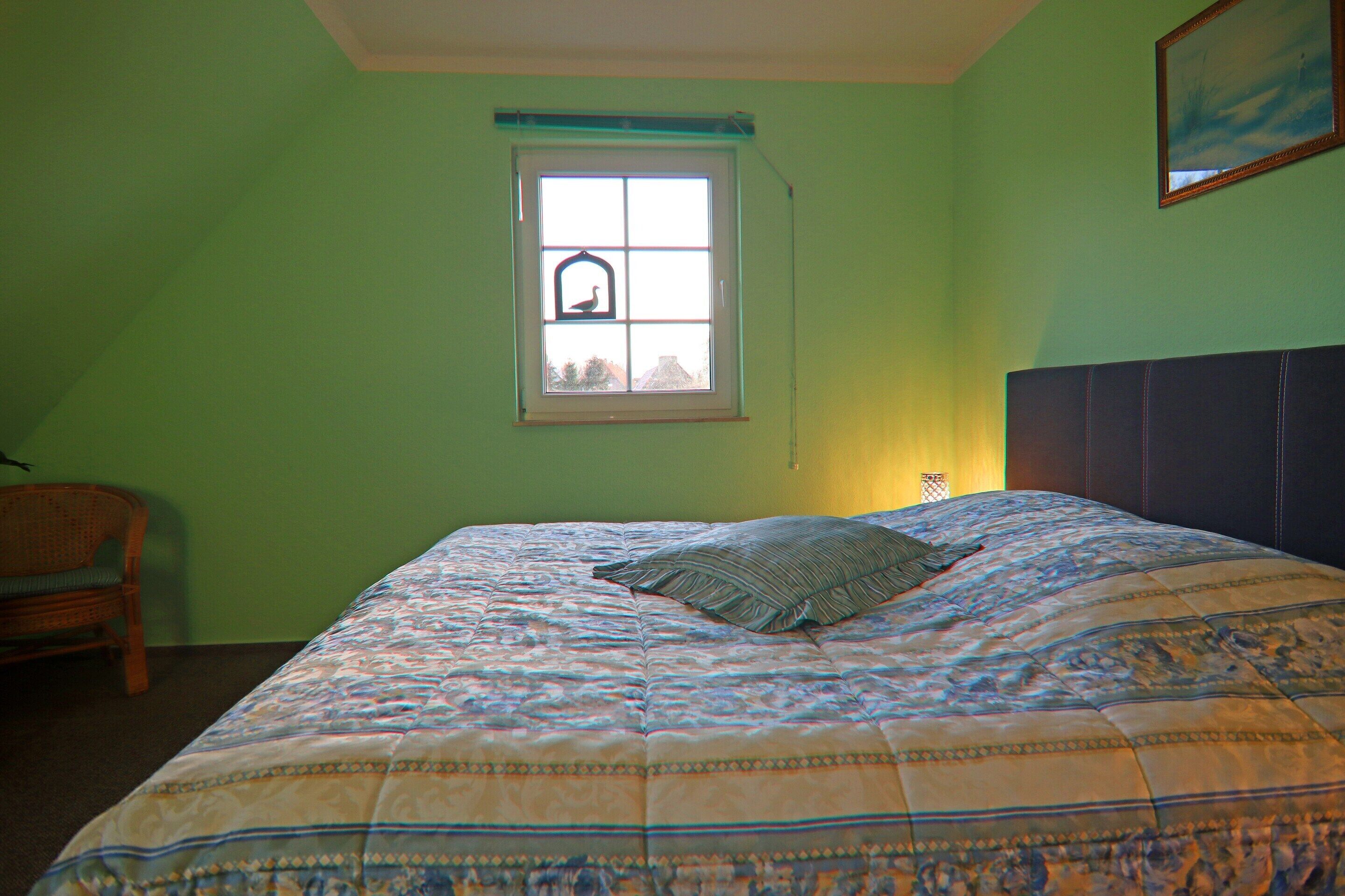 Un dormitorio con cama, ventana con vistas y una silla.