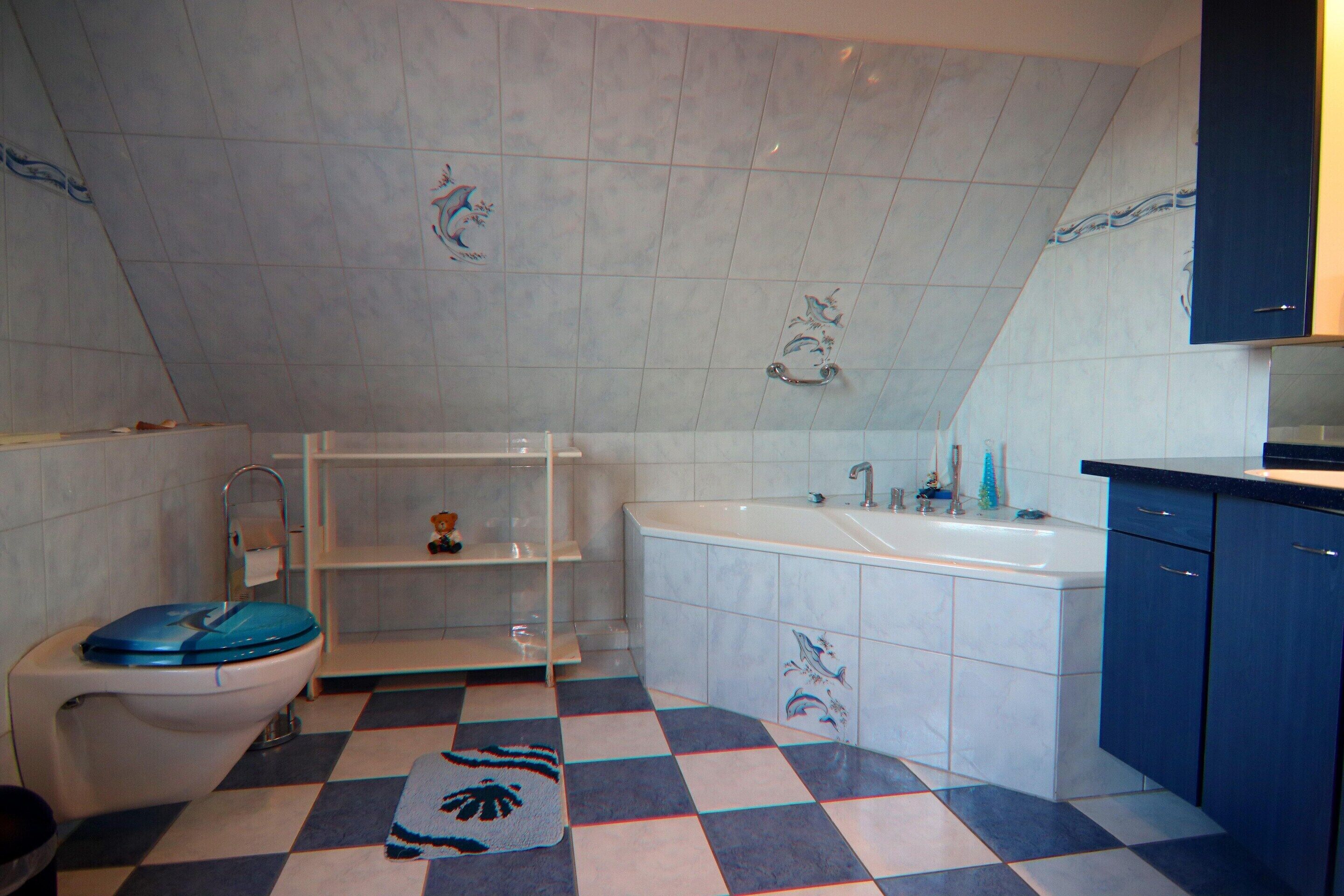 A bathroom with a checkered floor, a toilet with a blue seat, a bathtub, and a sink.