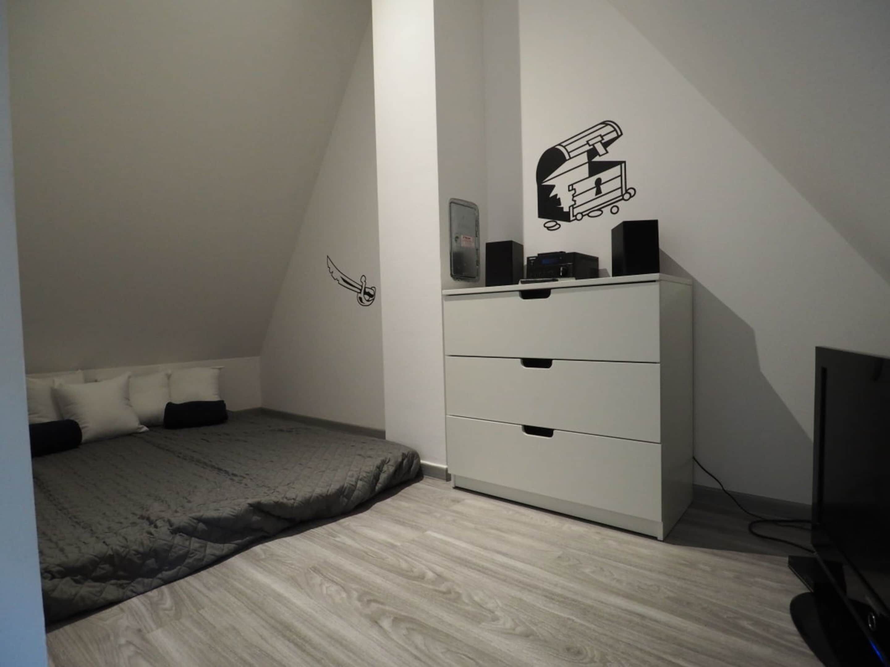 Un dormitorio con cama, cómoda y televisor.