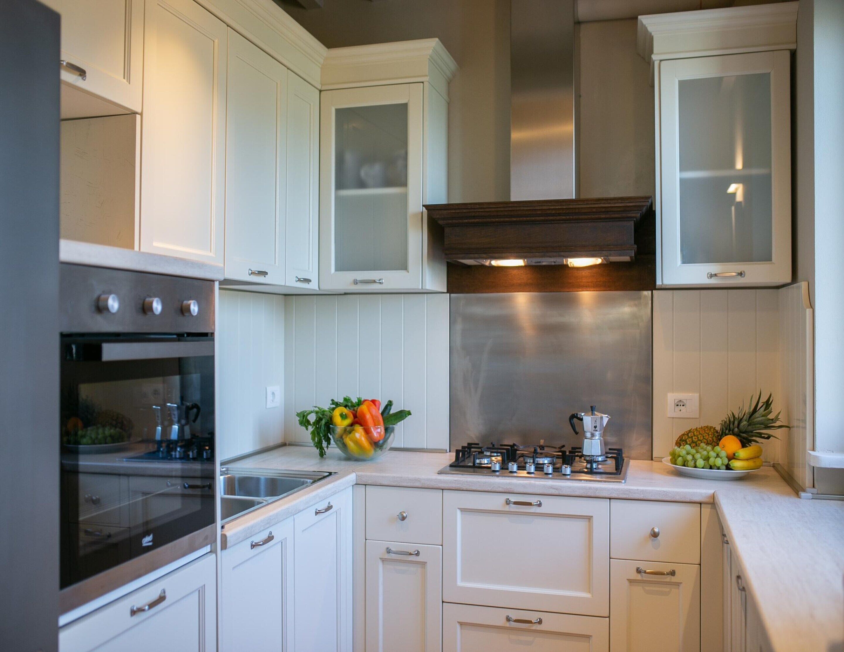 A modern kitchen with white cabinetry, a stainless steel range hood, and a gas stove.