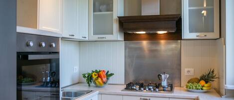 A modern kitchen with white cabinetry, a stainless steel range hood, and a gas stove.