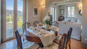 A dining area with a round table, chairs, and a view of the outdoors through large sliding doors. - Holiday Home in Cortona With Pool & Valley Views (Cortona)
