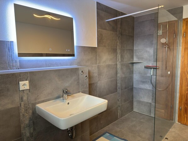 A modern bathroom with a white sink, a glass shower enclosure, and a wooden door. - Ruhiges Ferienhaus in Zingst-urlaub Nahe am Strand (Zingst)