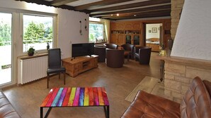 Uma sala de estar ampla com lareira, móveis de madeira e televisão.