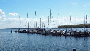 Een jachthaven met meerdere zeilboten afgemeerd bij houten steigers.