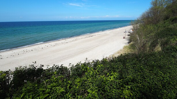 Een strand met helderblauw water en een zandstrand.
