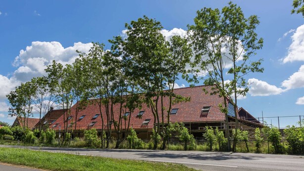 A large building with multiple red-tiled roofs, surrounded by trees and a clear sky. - Scenic Holiday Home in Oostkapelle near Beach (Oostkapelle)