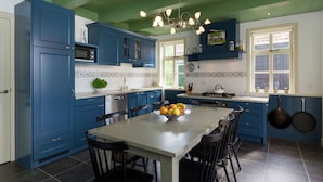 A kitchen with blue cabinets, a white island, and a chandelier. - Scenic Holiday Home in Oostkapelle near Beach (Oostkapelle)