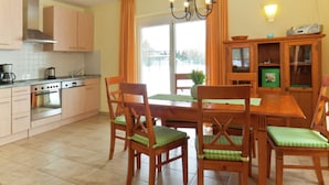 A kitchen with wooden cabinets, a stove, and a dining table with chairs. - Gemutliche Ferienwohnung in Satow (Satow)