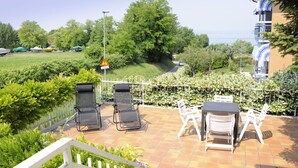 Eine Terrasse mit Sitzgelegenheit, Blick auf das Meer und üppiger Vegetation.
