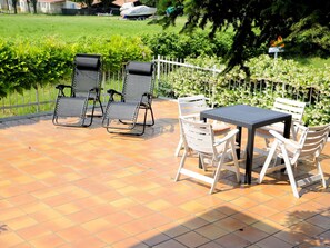An outdoor patio with a table and chairs, surrounded by a white fence and greenery. - Near the Harbour and Sandbeach of Pacengo di Lazise (Lazise)