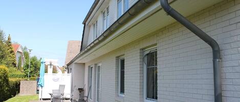A two-story house with a brick exterior, a tiled roof, and a visible gutter system.