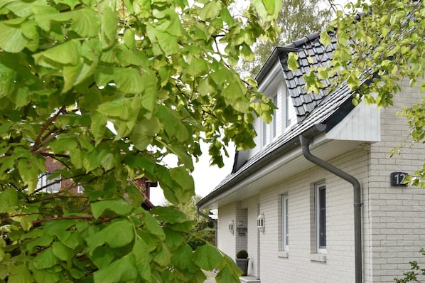 En vit tegelbyggnad med ett mörkt tak, numrerad med 12, och ett väl synligt fönster.