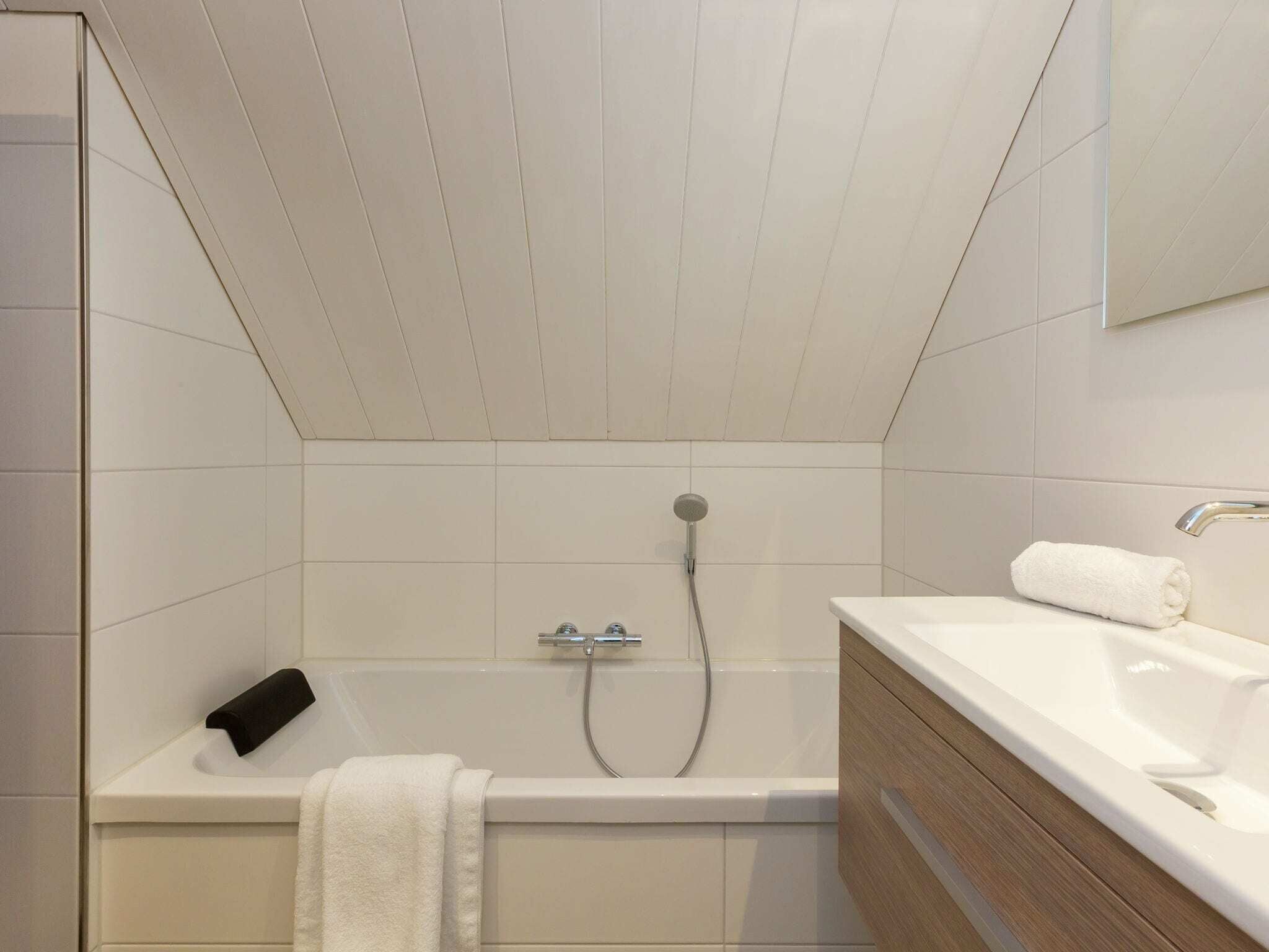 A modern bathroom with a bathtub, a sink, and a mirror.