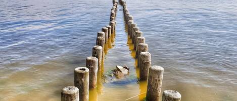 A wooden pier extending into calm waters, surrounded by clear skies.