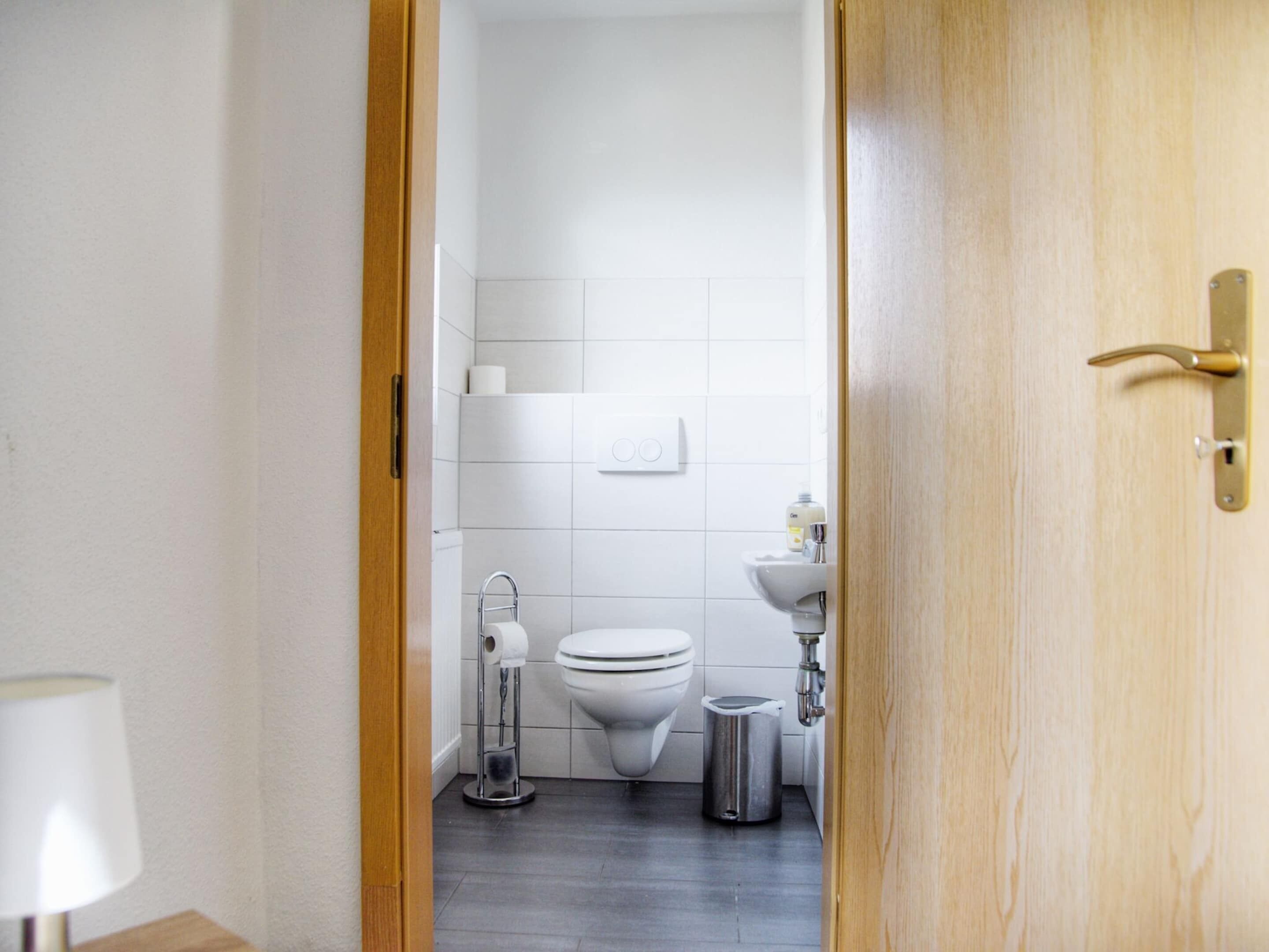 Une salle de bain moderne équipée de toilettes, d’un lavabo et d’un sèche-mains.