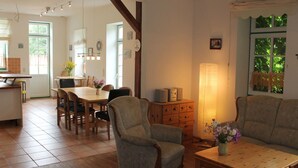 Ein geräumiger Wohnbereich mit einem Holzesstisch, zwei Sesseln, einem Sofa und einer Lampe.