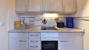 A kitchen with light wood cabinets, a built-in oven, a coffee maker, and a kettle. - Attractive Bungalow in Damshagen near Sea (Damshagen)
