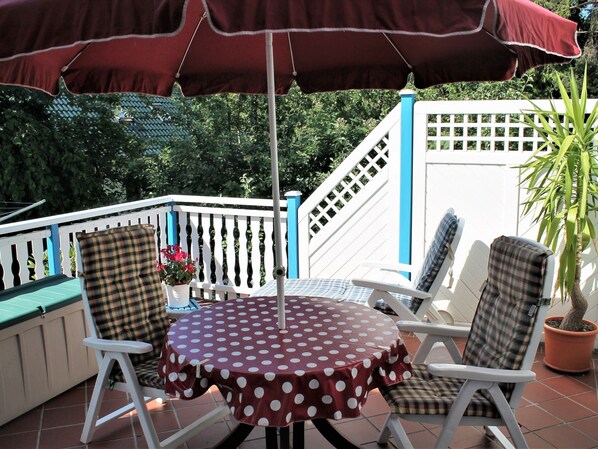 A patio with a round table covered with a polka dot tablecloth, surrounded by white chairs with plaid cushions. - Attractive Bungalow in Damshagen near Sea (Damshagen)