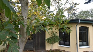 Una casa con un sendero de ladrillo que conduce a una puerta de madera, rodeada de árboles y un pequeño jardín.
