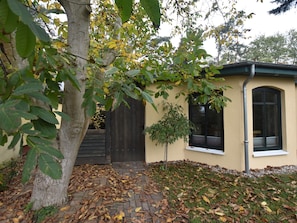 Ein Haus mit einem Ziegelweg, der zu einer Holztür führt, umgeben von Bäumen und einem kleinen Garten.