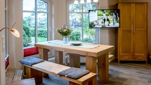 Una cocina moderna con una mesa de madera, bancos y un televisor montado en la pared.