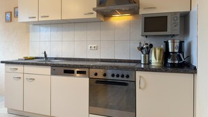 Una cocina moderna con armarios blancos, horno de acero inoxidable, microondas integrado y cafetera.