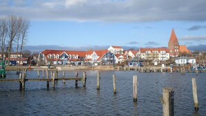 Un pueblo frente al mar con edificios tradicionales y una destacada torre de iglesia.
