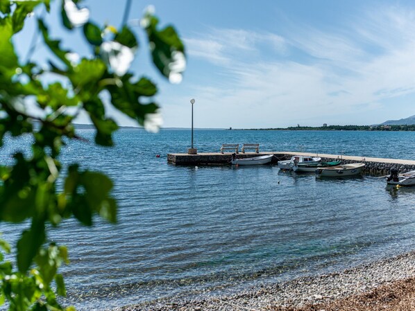 A calm lake with boats docked at a pier, surrounded by greenery.