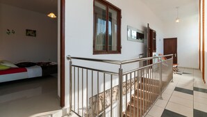 Une pièce spacieuse comprenant un lit, une fenêtre et un escalier menant à un autre niveau.