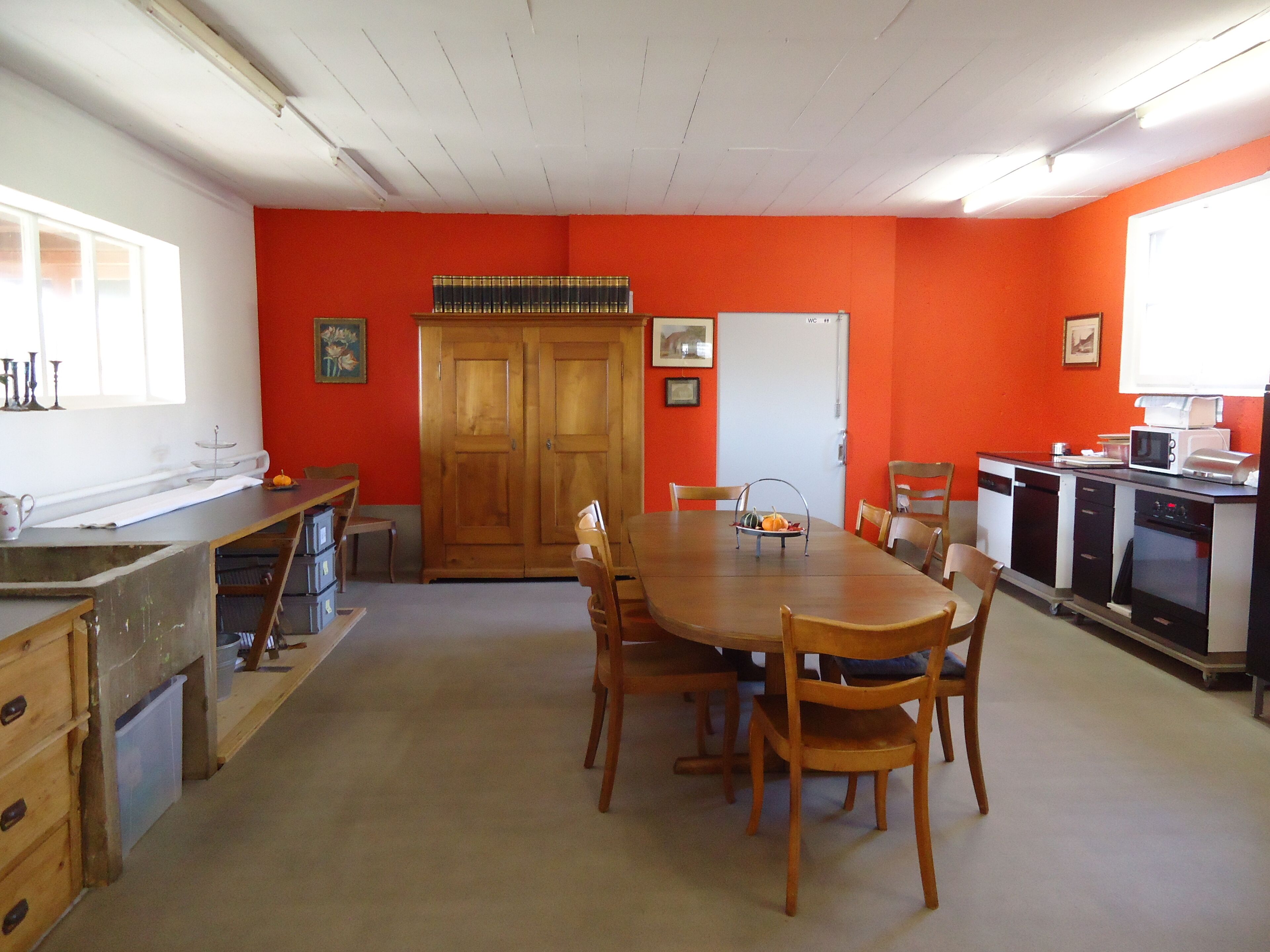 A dining area with a wooden table and chairs, a kitchen area with appliances, and a door marked "WC".