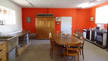A dining area with a wooden table and chairs, a kitchen area with appliances, and a door marked "WC".