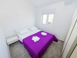 A bedroom with a bed, a window, and a nightstand.