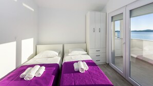 Une chambre d’hôtel moderne avec deux lits, une armoire et un balcon offrant une vue sur la mer.