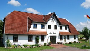 A two-story building with a red-tiled roof, a sign reading "Alte Schule," and a German flag. - Wohnung in Dargun, Mecklenburg mit Schwimmbad (Dargun)