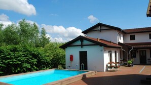 A swimming pool with a wooden deck, a small building with a door, and a patio area with outdoor furniture. - Wohnung in Dargun, Mecklenburg mit Schwimmbad (Dargun)